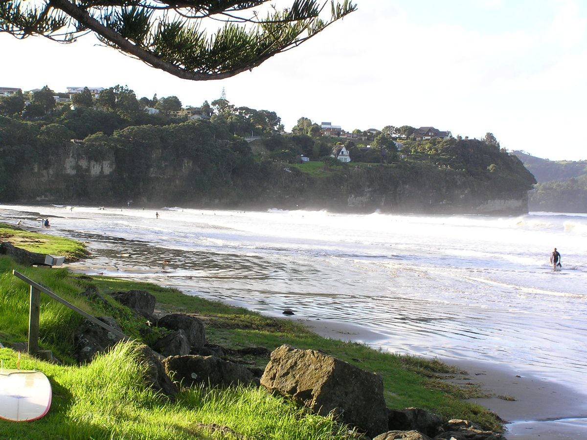 Surfers and waves at Albany beach just north of Auckland New Zealand