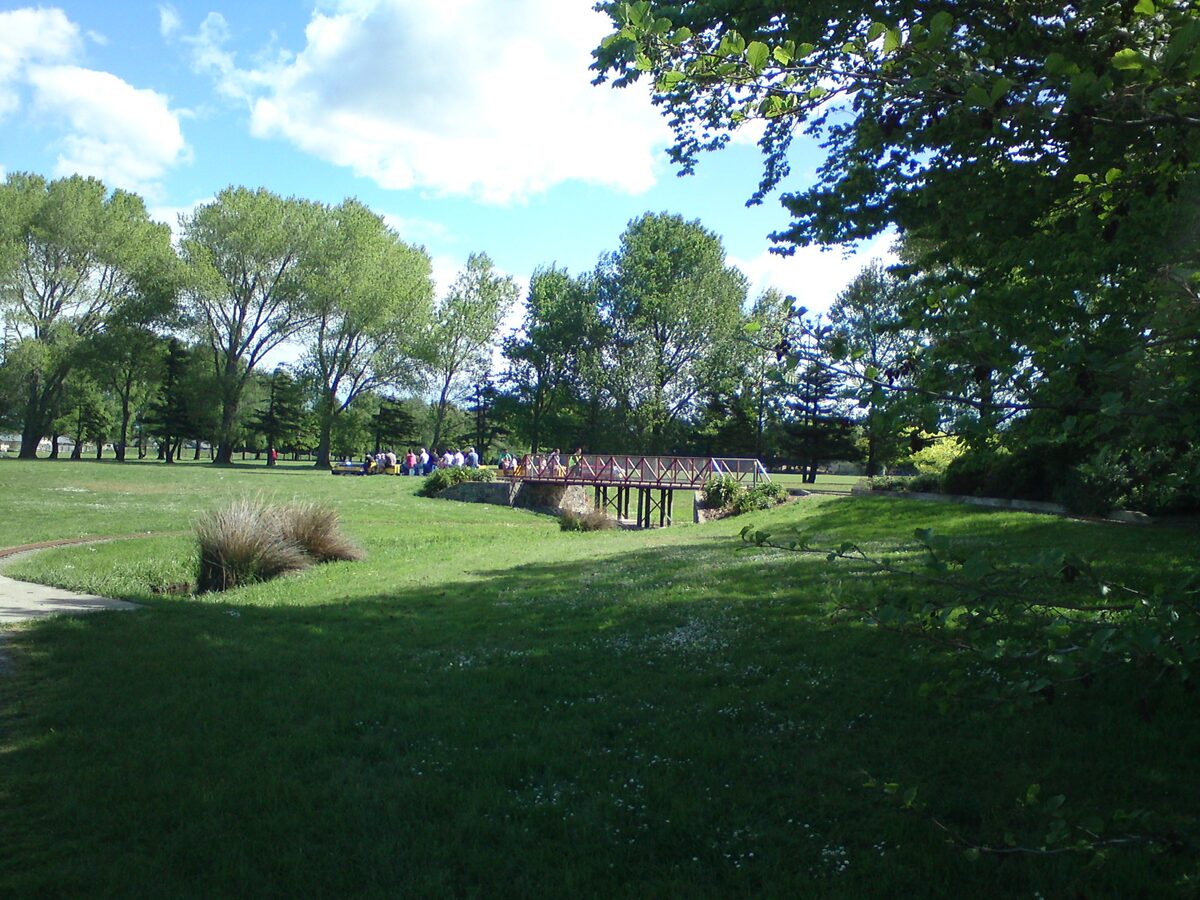 Halswell Domain park with bridge over stream and mature trees on a sunny day Christchurch