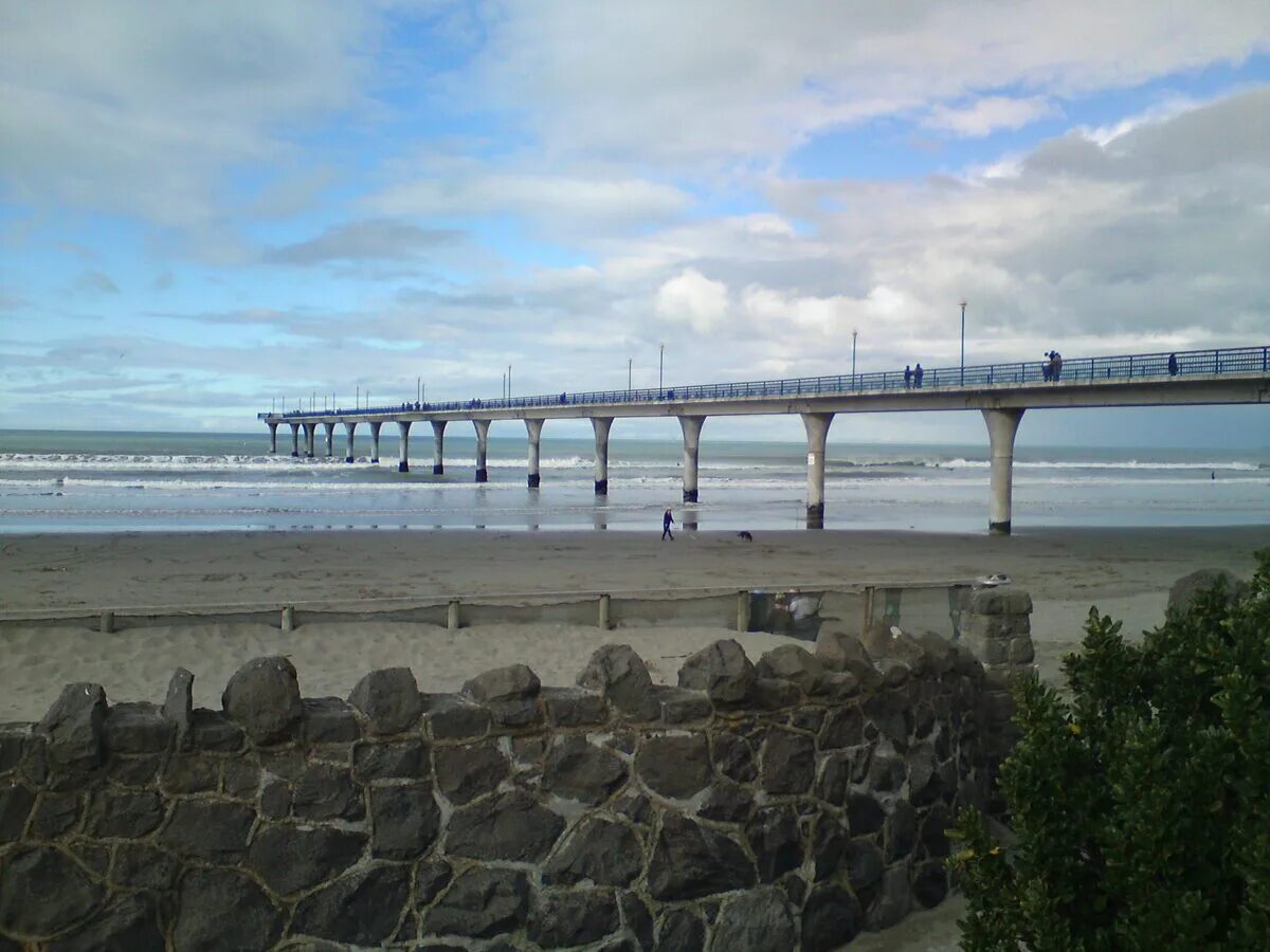 New Brighton Pier stretching into the ocean with beach and dramatic sky Christchurch New Zealand