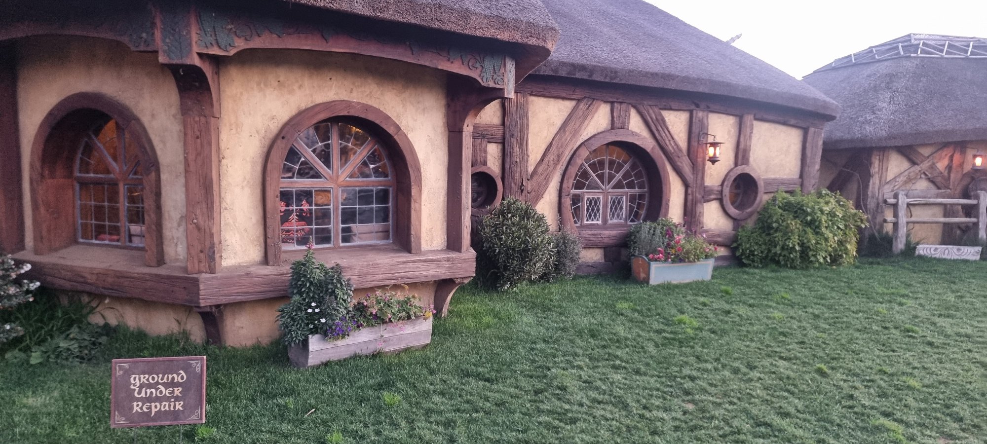 The Green Dragon Inn exterior with thatched roof, round windows and flower boxes at Hobbiton Movie Set