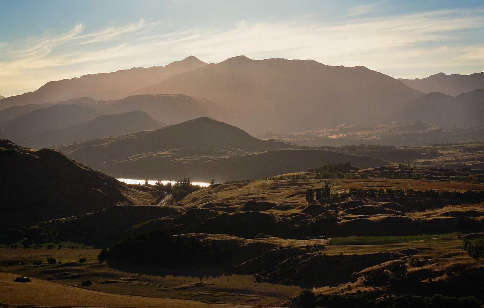 Snow-capped New Zealand mountains reflected in a still lake at sunset