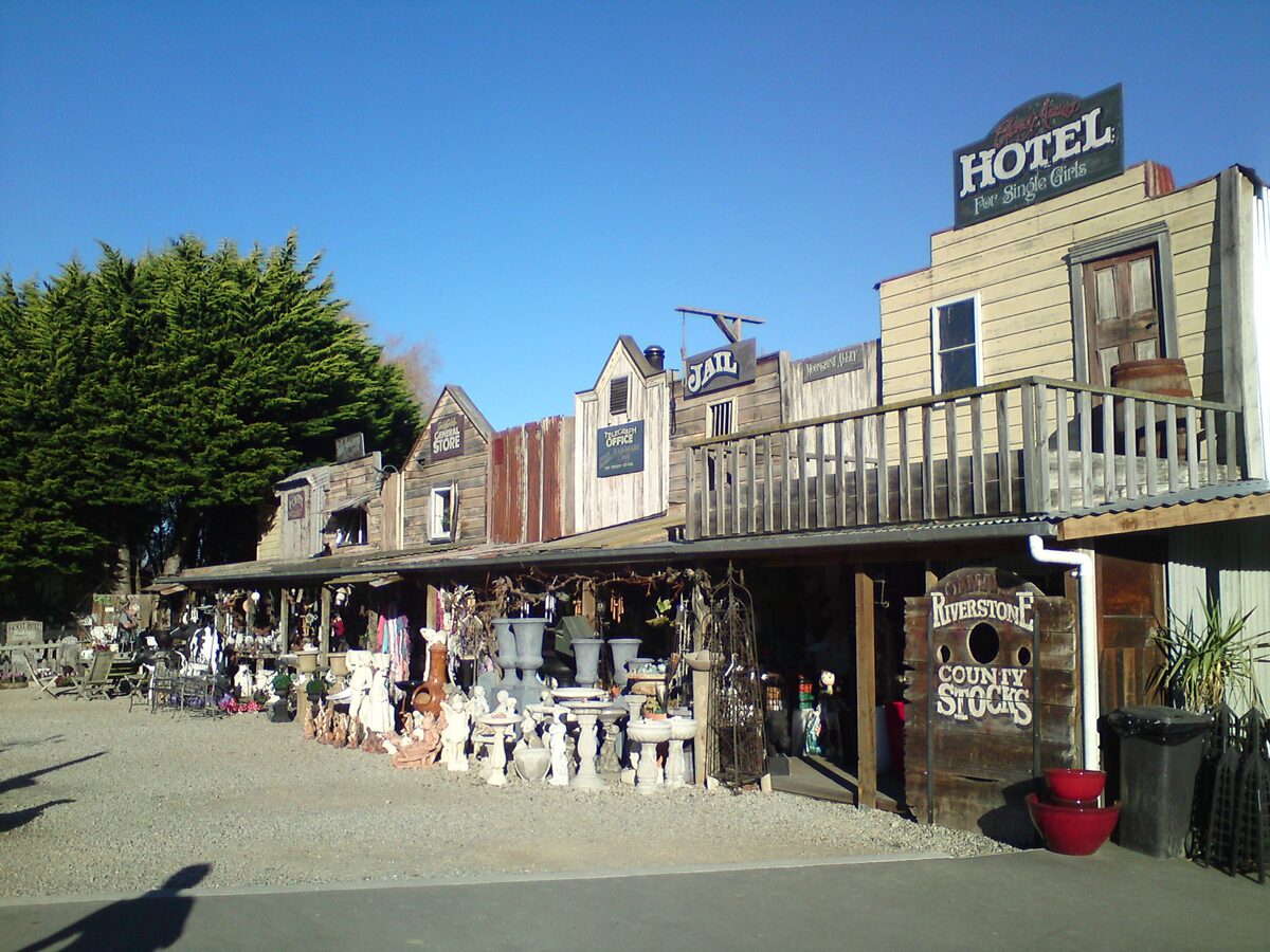 Riverstone curio shops with old west style facades including Hotel Jail and County Stocks signs near Oamaru