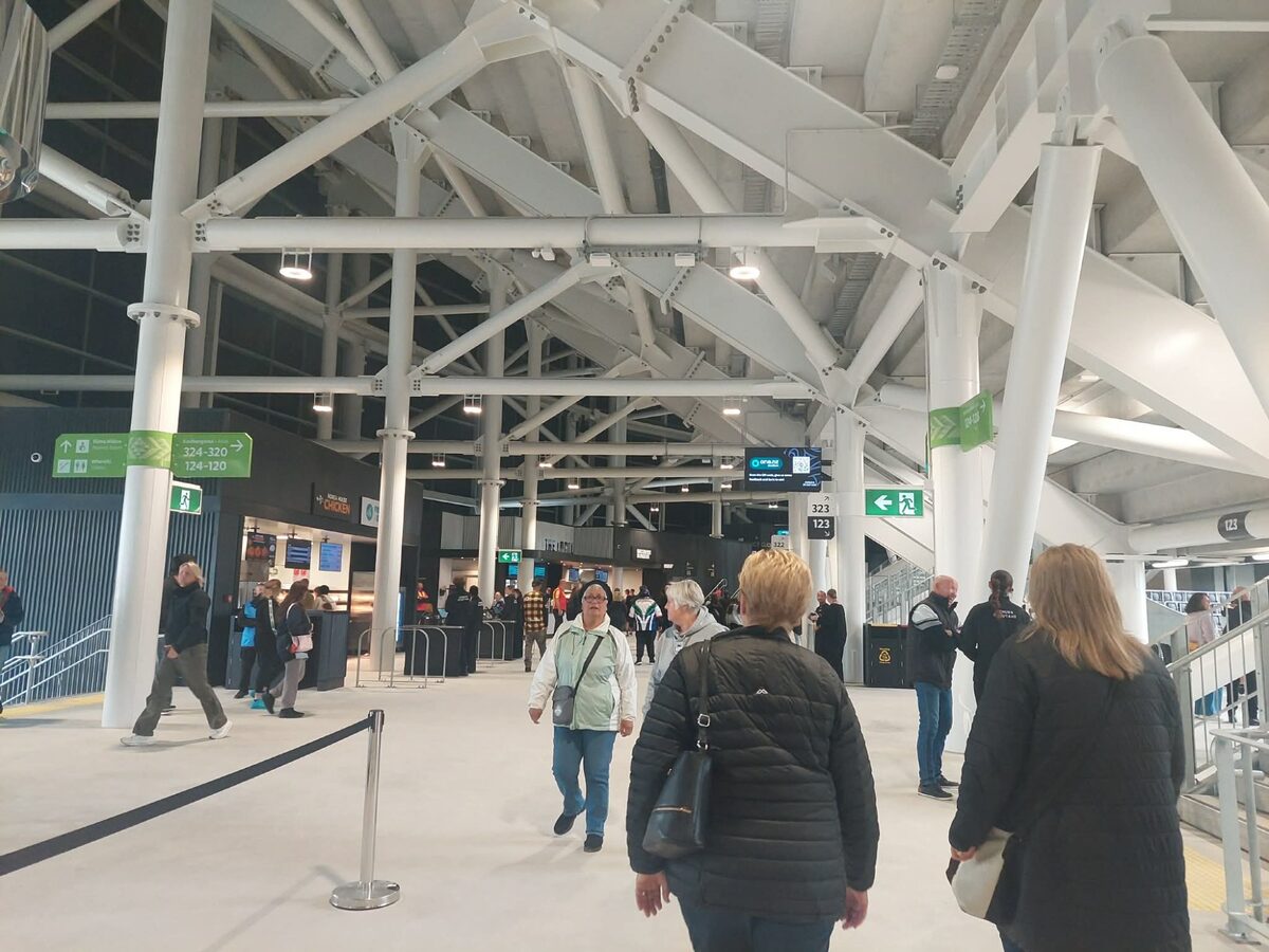Wide concourse inside One NZ Stadium with food stands and wayfinding signage