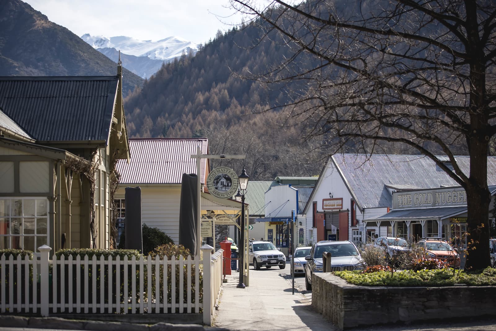 Arrowtown historic main street with The Gold Nugget shop and snow-capped mountains behind