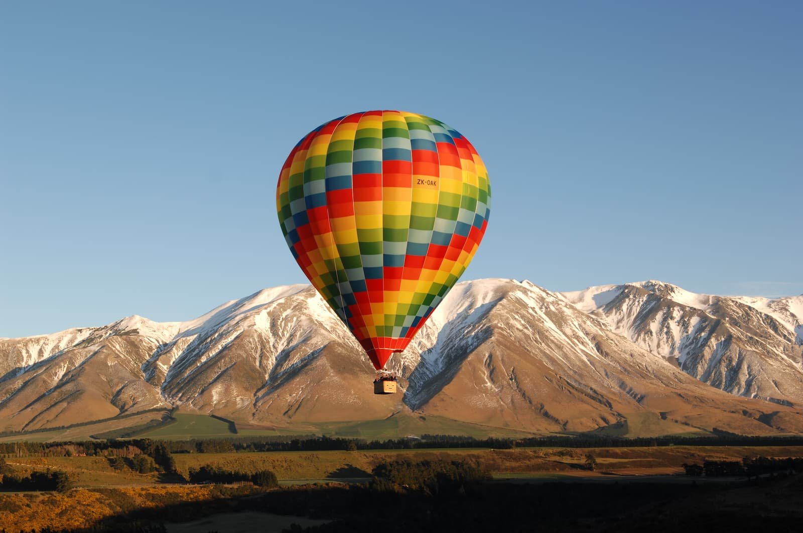 Hot air balloon floating over the Canterbury Plains with Southern Alps behind Christchurch New Zealand