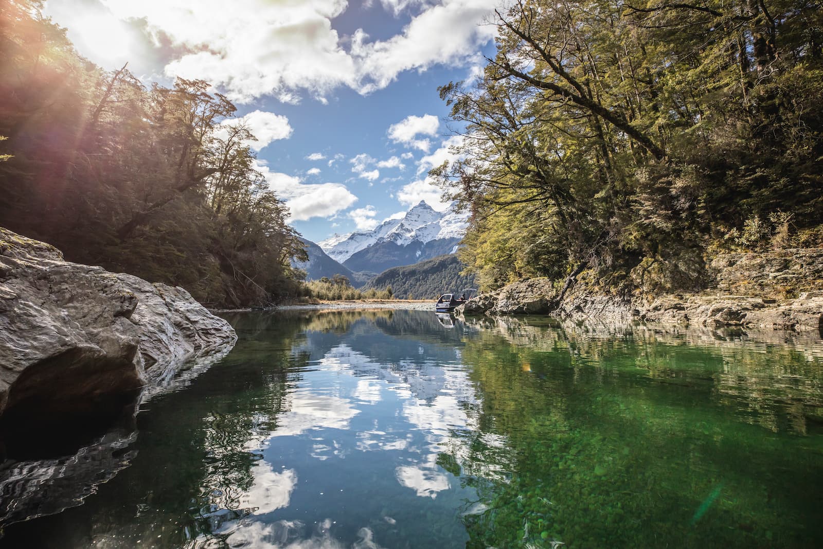 Dart River jet boat through beech forest with snow mountains near Glenorchy Queenstown