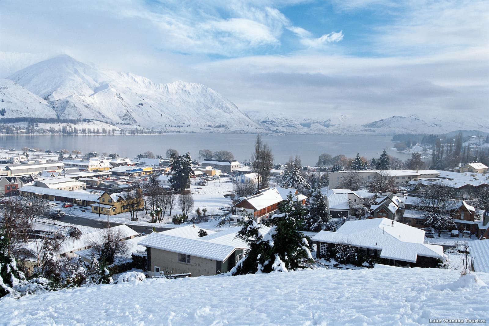 Wanaka township covered in snow with Lake Wanaka and mountains behind winter