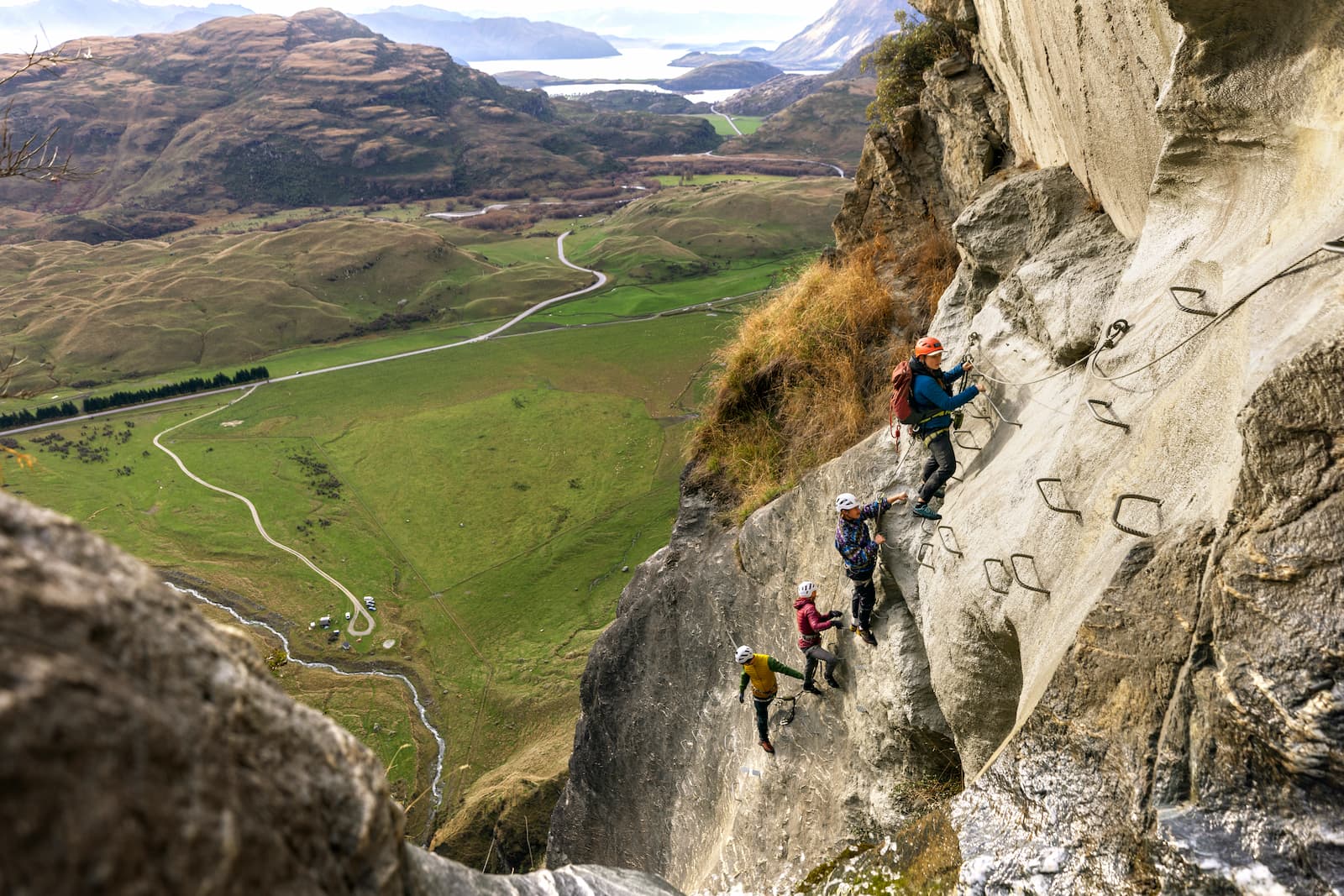 Family on a via ferrata rock climbing adventure near Wanaka with Lake Wanaka in the distance