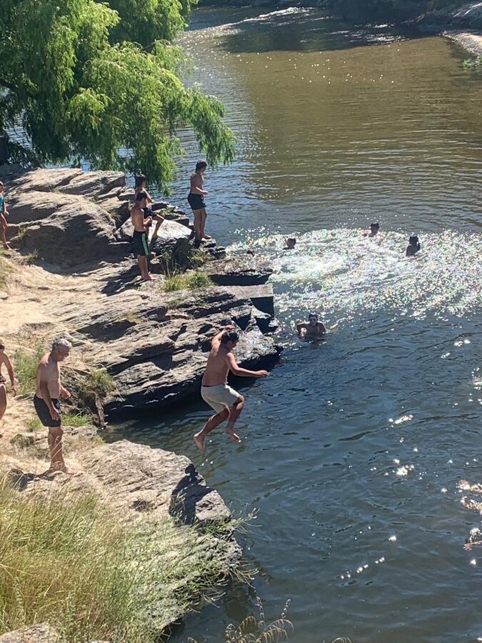 Kids cliff jumping into the river on a hot summer day near Wanaka Central Otago New Zealand